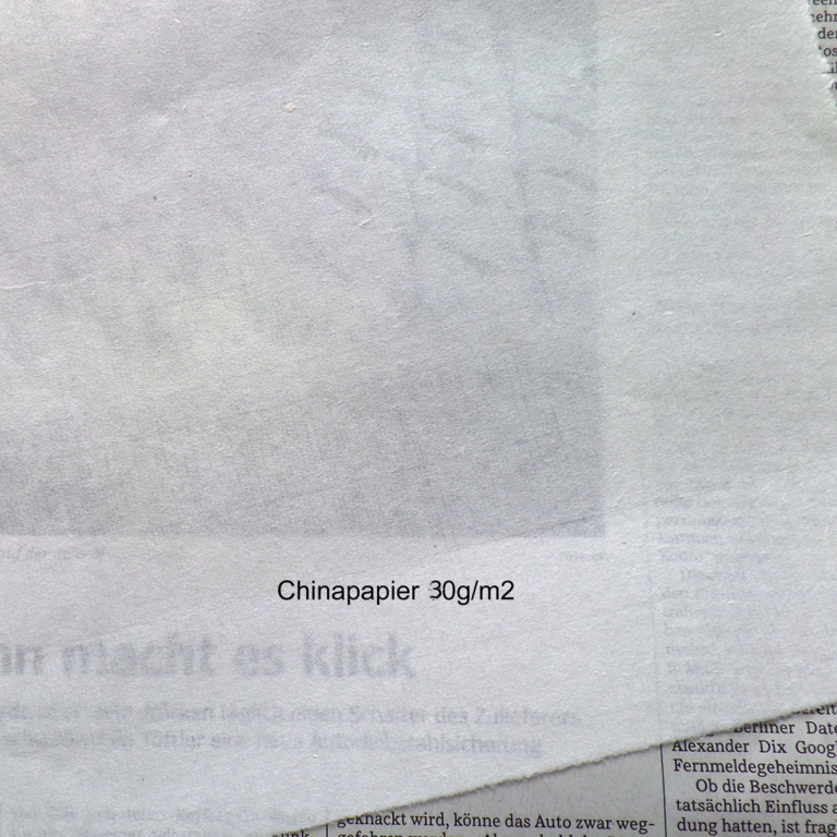 Durch dünnes Chinapapier kann er darunterliegende Zeitungsartikel lesen.